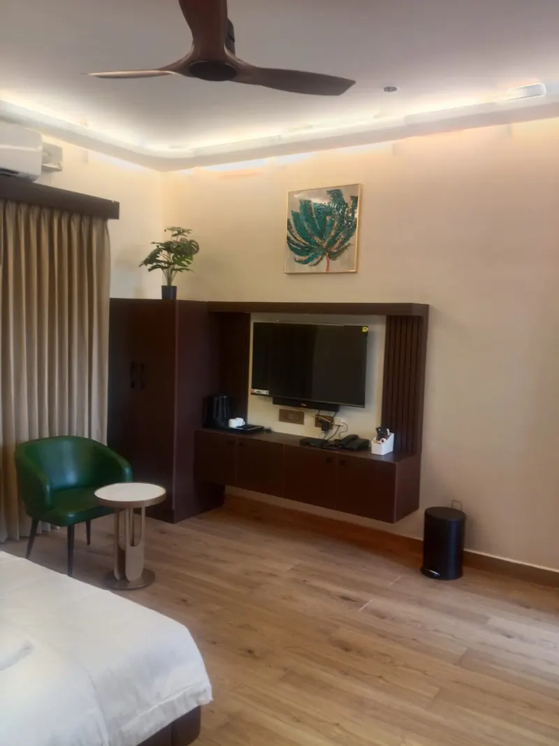 Room interior with flat-screen TV, armchair and kettle at Sai Grand Resorts, Kumbakarai
